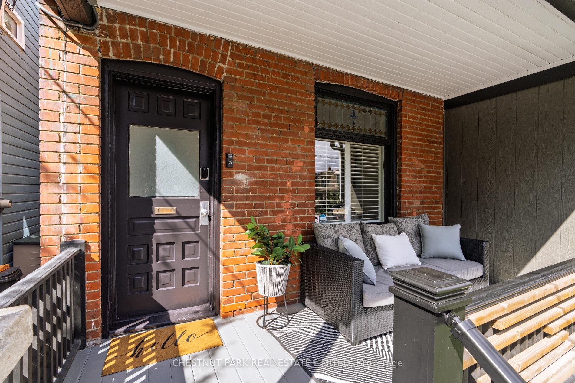 Covered brick front porch with a black door, stained-glass transom, and wicker seating area.