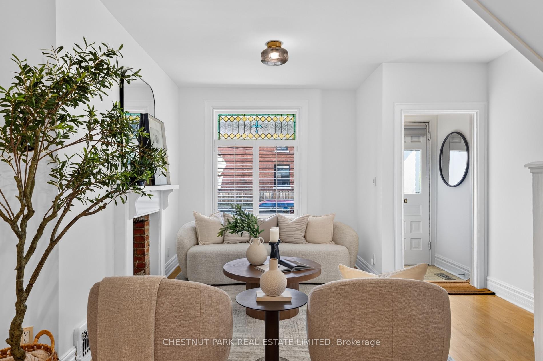 Staged living room with cream sofas, a white fireplace, and a stained-glass window.