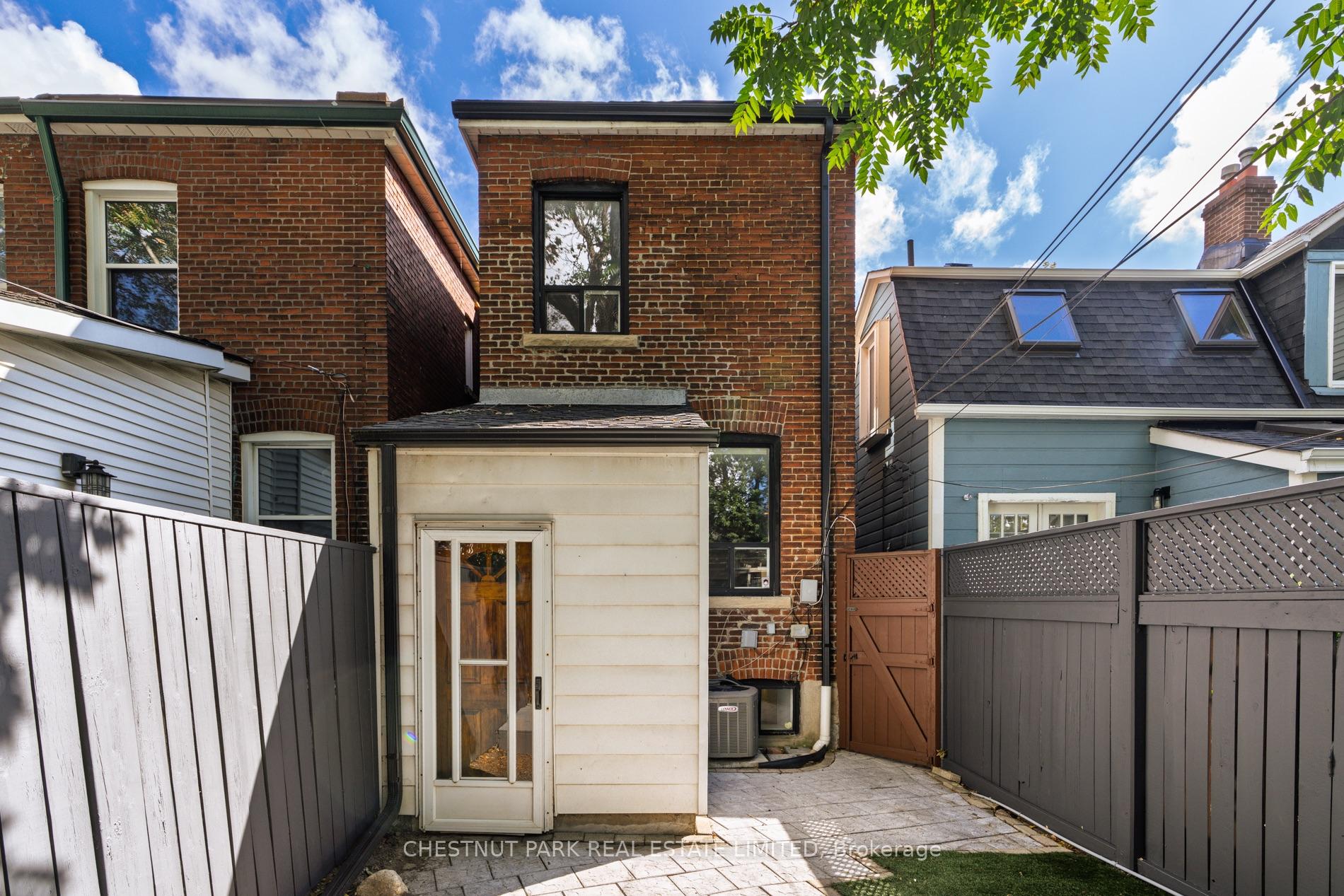 Rear of a red-brick house, with a paved patio, fenced yard, and neighboring homes.