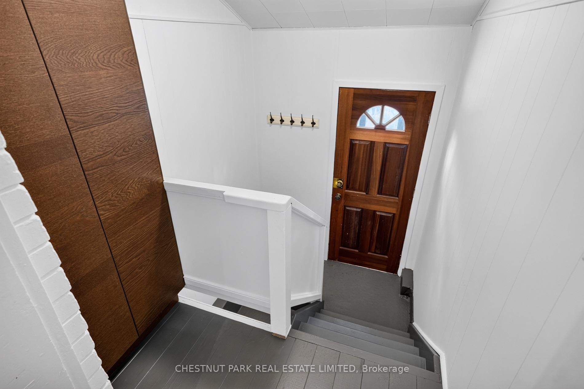 Staircase descending to a dark wood front door with a fanlight window and white paneled walls.