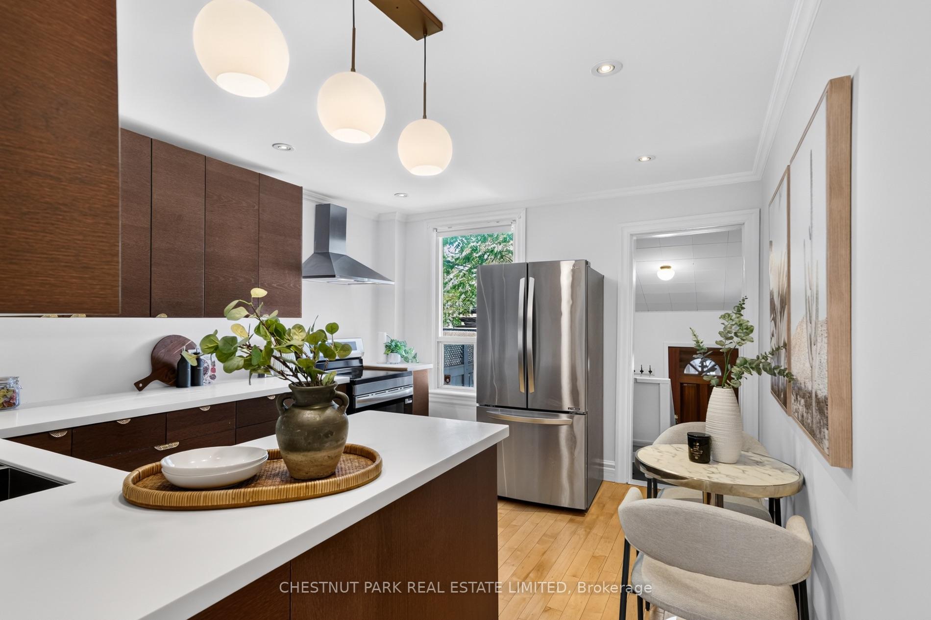 Modern kitchen with dark wood cabinetry, a white island, stainless appliances, and a compact dining nook.