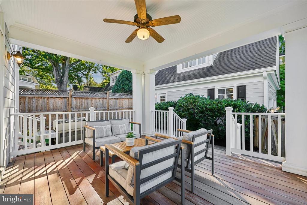 Covered rear deck with wood flooring, white railings, and a furnished outdoor seating area.