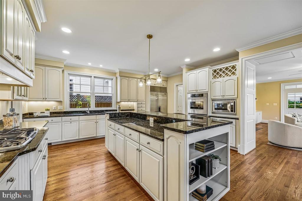 Spacious kitchen with cream cabinetry, granite counters, stainless steel appliances, and a large central island.