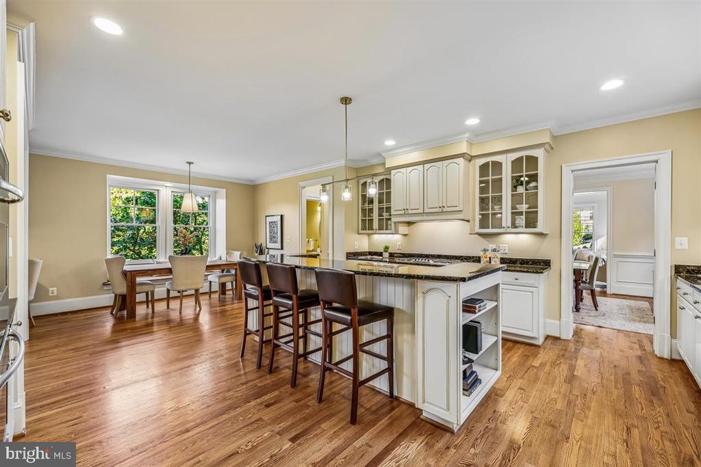 Kitchen and dining area with a large island, white cabinetry, and hardwood floors.