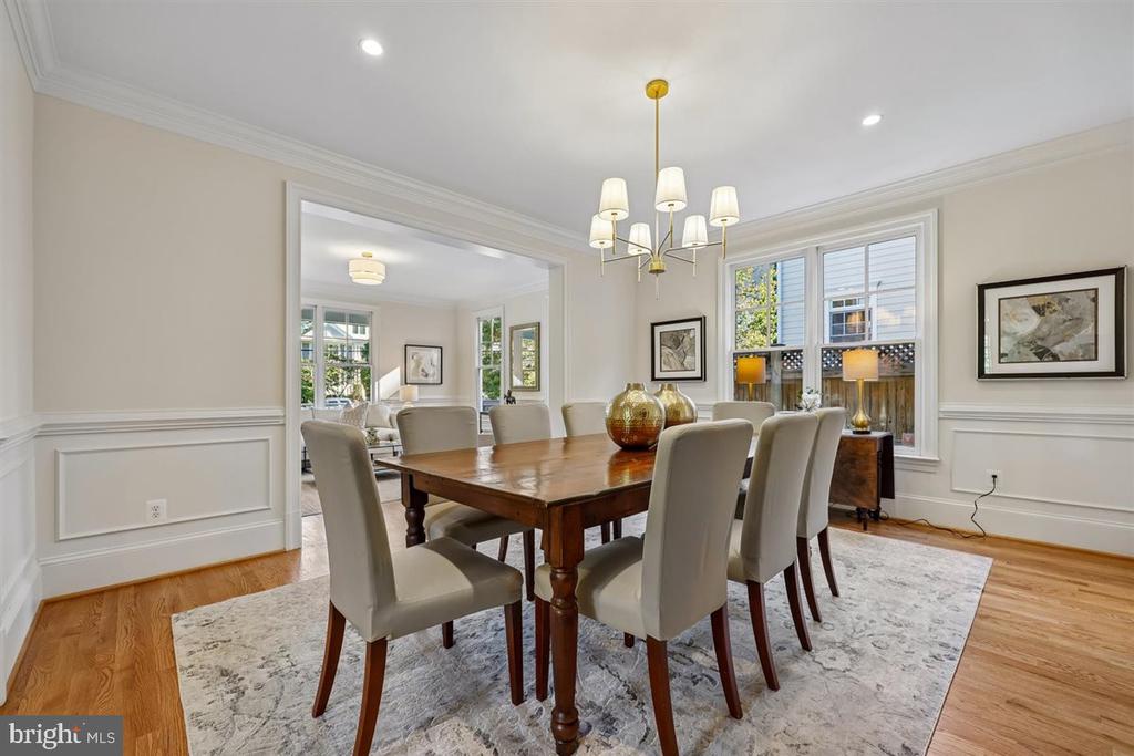Dining room with a dark wood table, upholstered chairs, chandelier, and large windows.