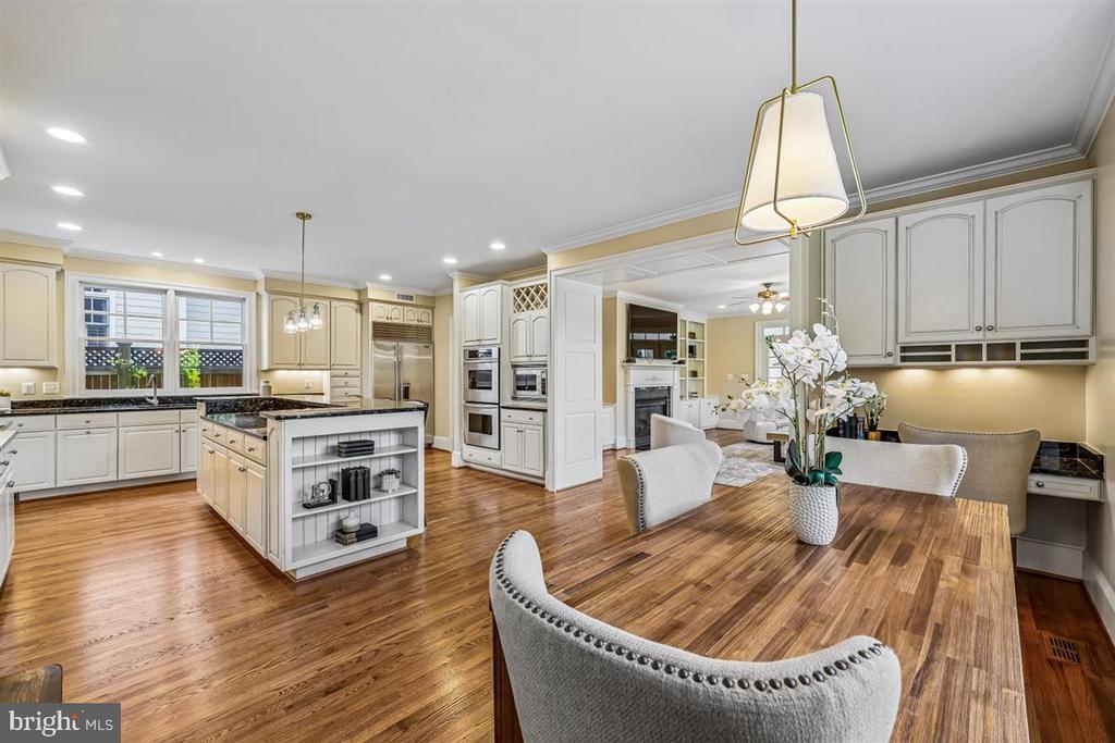 Kitchen and dining area with white cabinetry, a central island, and hardwood floors.
