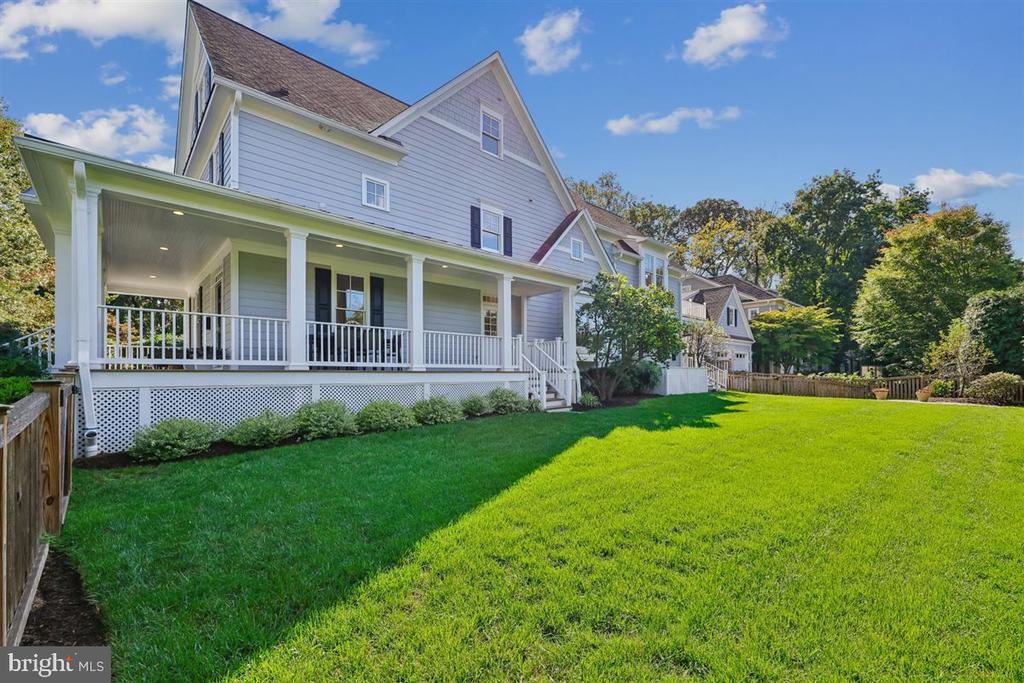 Two-story house with a long covered porch overlooking a broad green lawn.