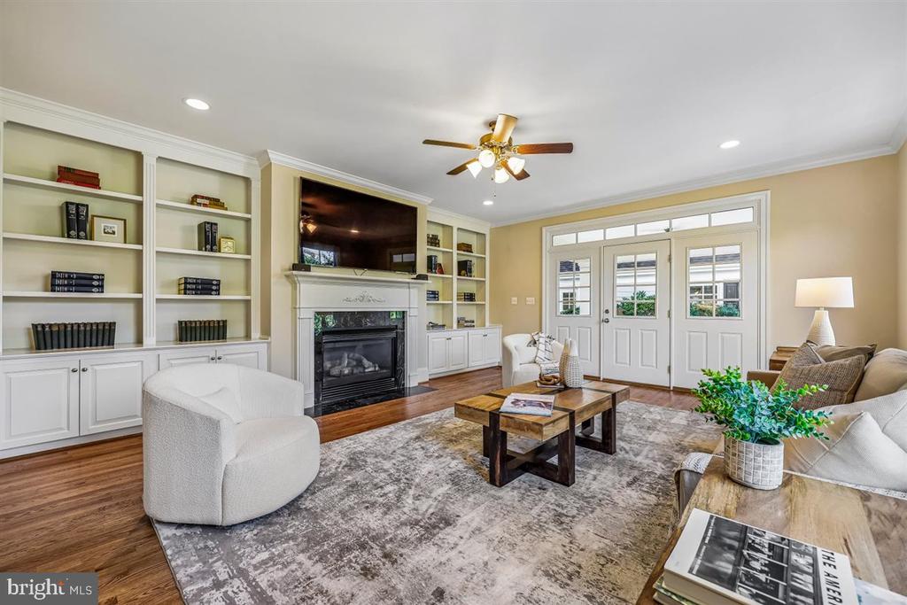 Living room with built-in bookshelves, a fireplace, and white French doors.