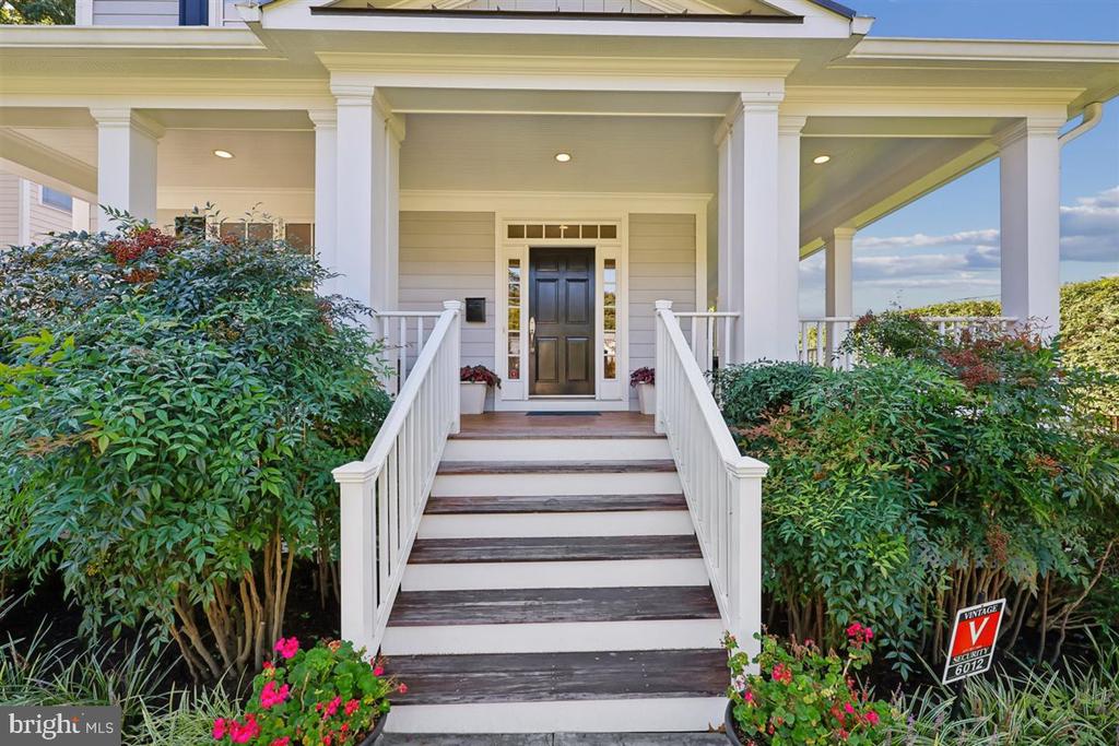 House entrance with a covered porch, white columns, broad steps, and a dark front door.