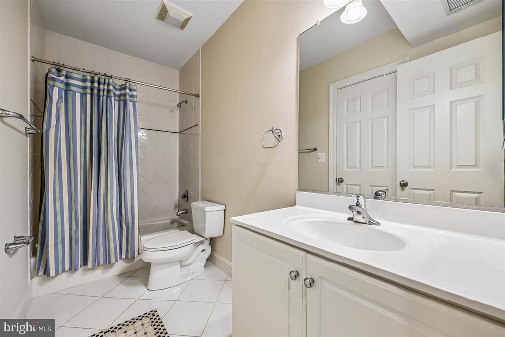 Bathroom with a white vanity, large mirror, and striped shower curtain over the tub.