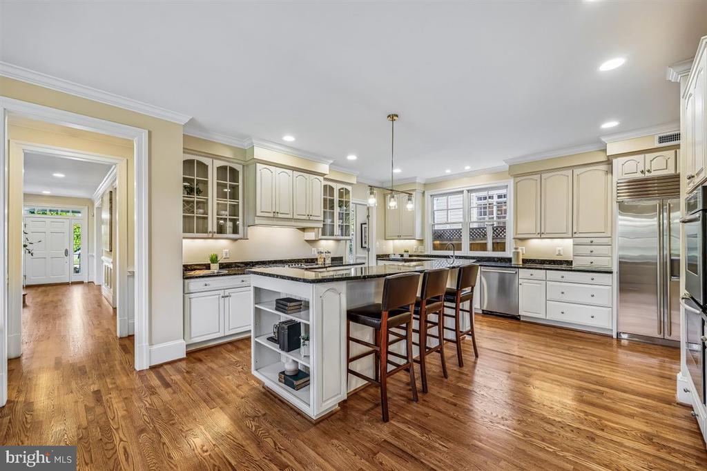Kitchen with a large island, dark countertops, cream cabinets, and hardwood floors.