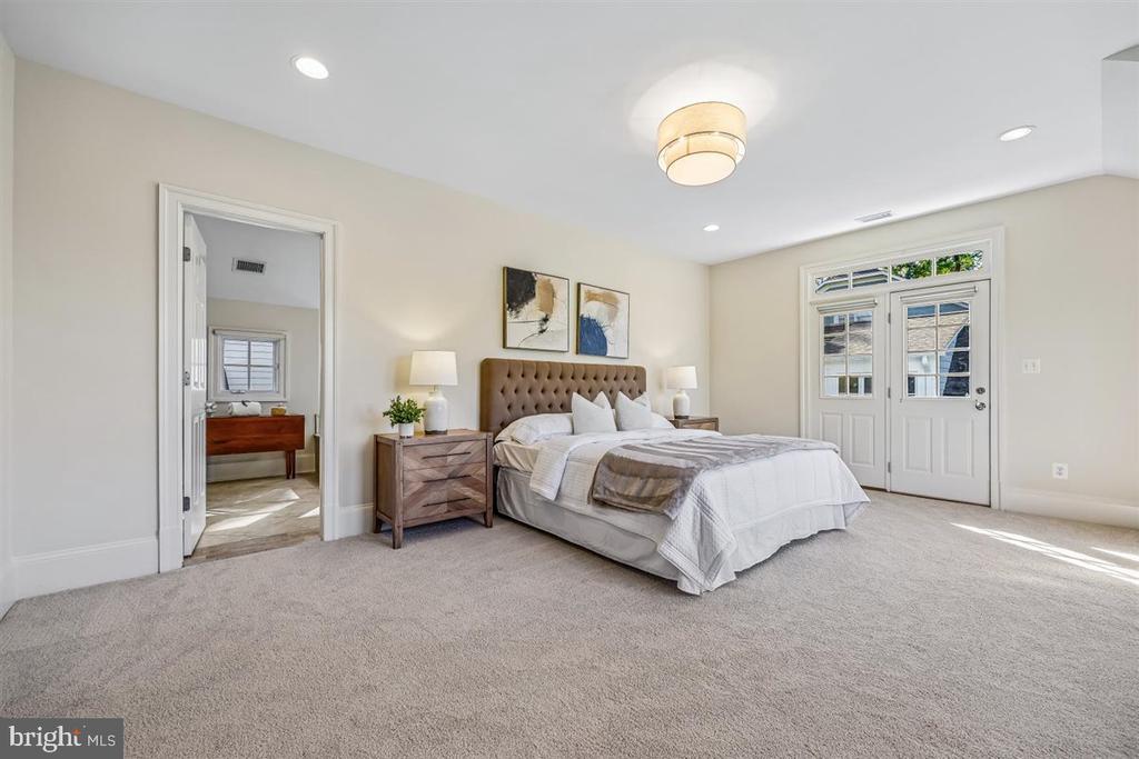 Furnished bedroom with a tufted bed, neutral carpet, and glazed double doors.