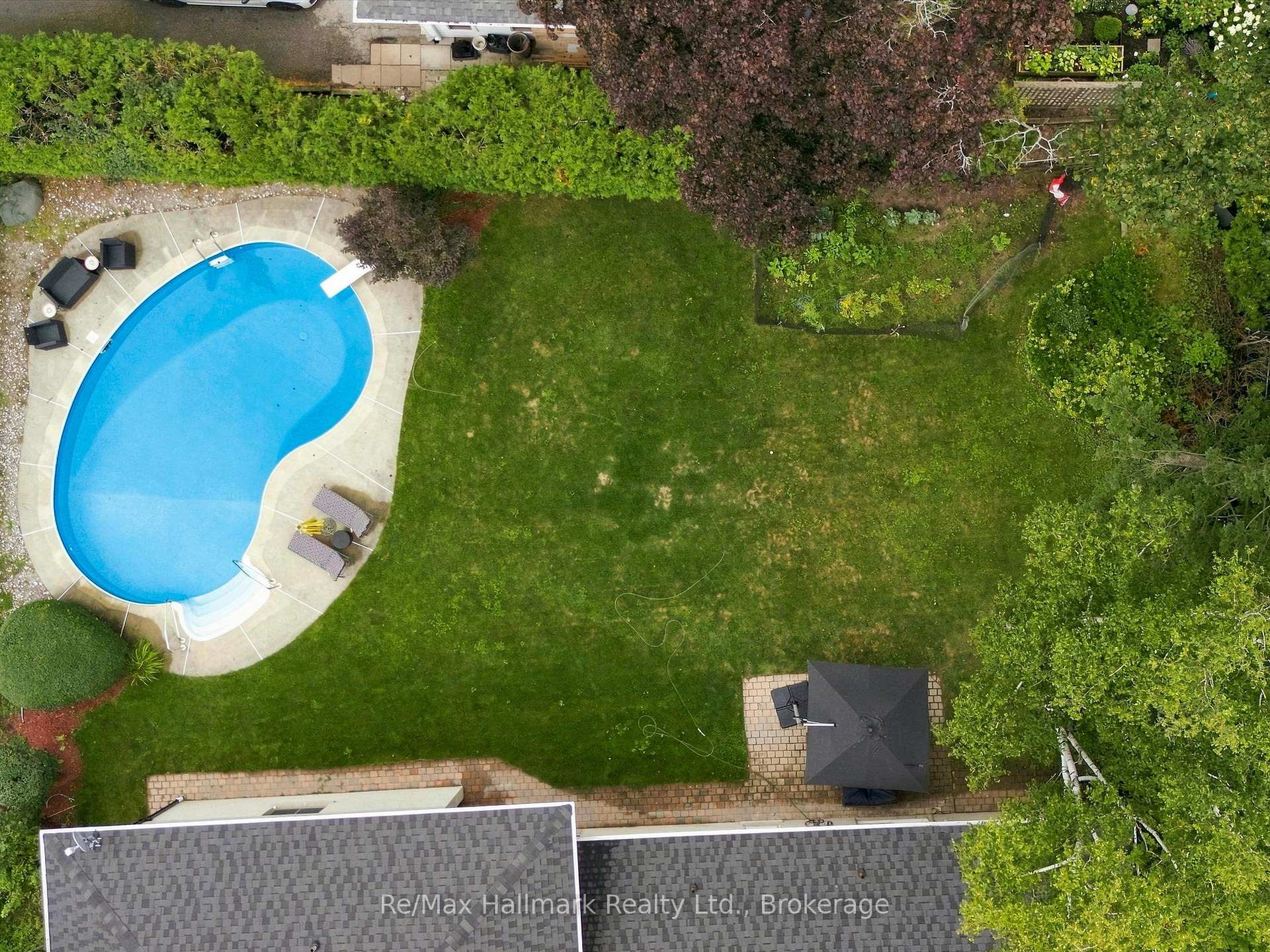 Aerial view of a landscaped backyard with a kidney-shaped pool, patio, and gazebo.