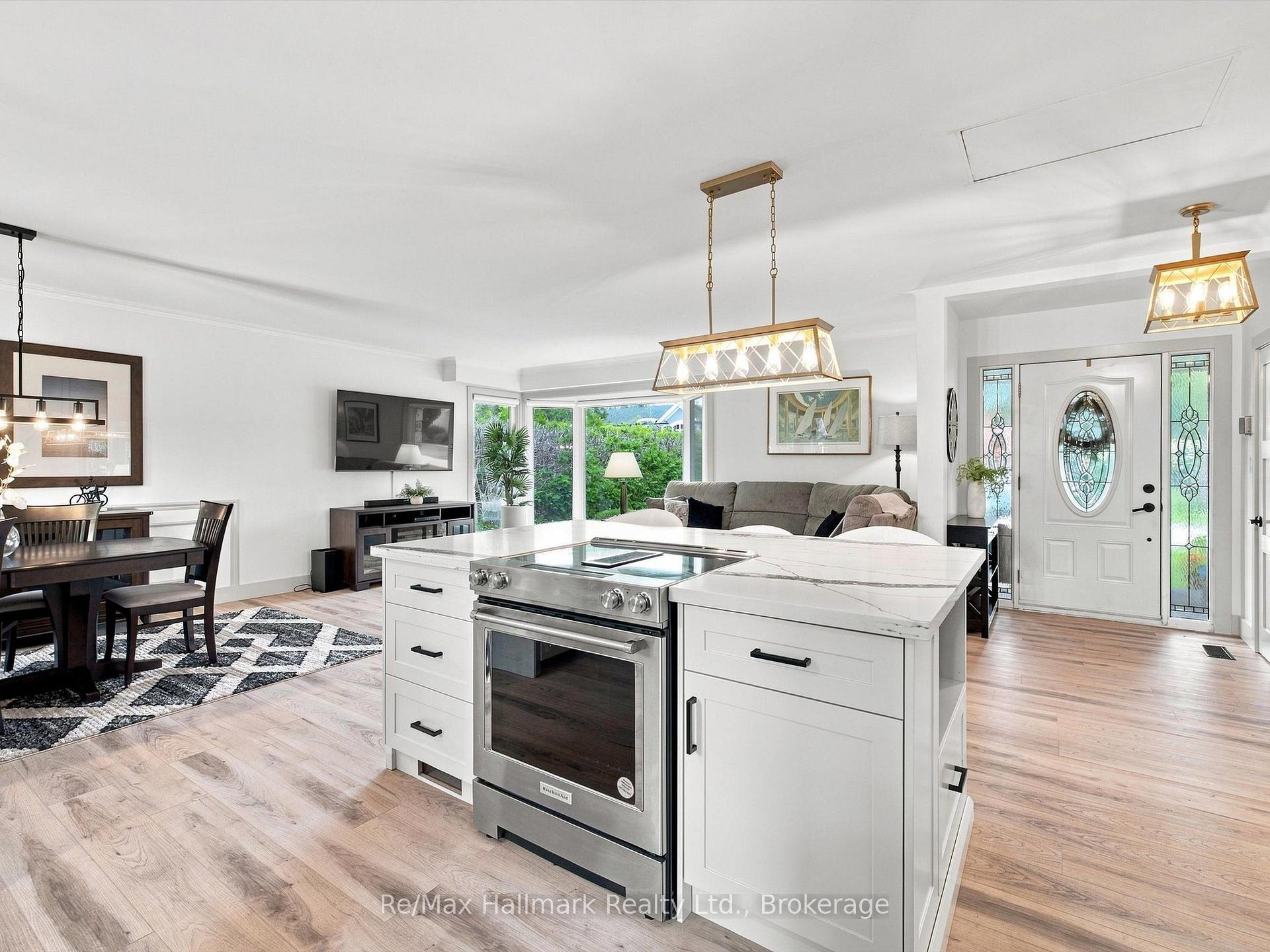Open-concept kitchen with a large island and stainless-steel range beside the dining and living areas.