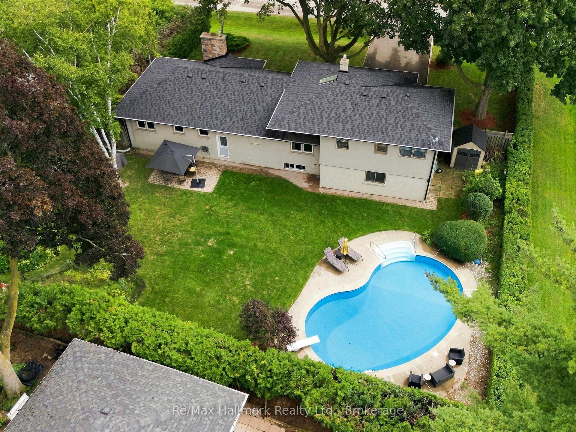 Aerial view of a house and landscaped backyard with a kidney-shaped swimming pool.