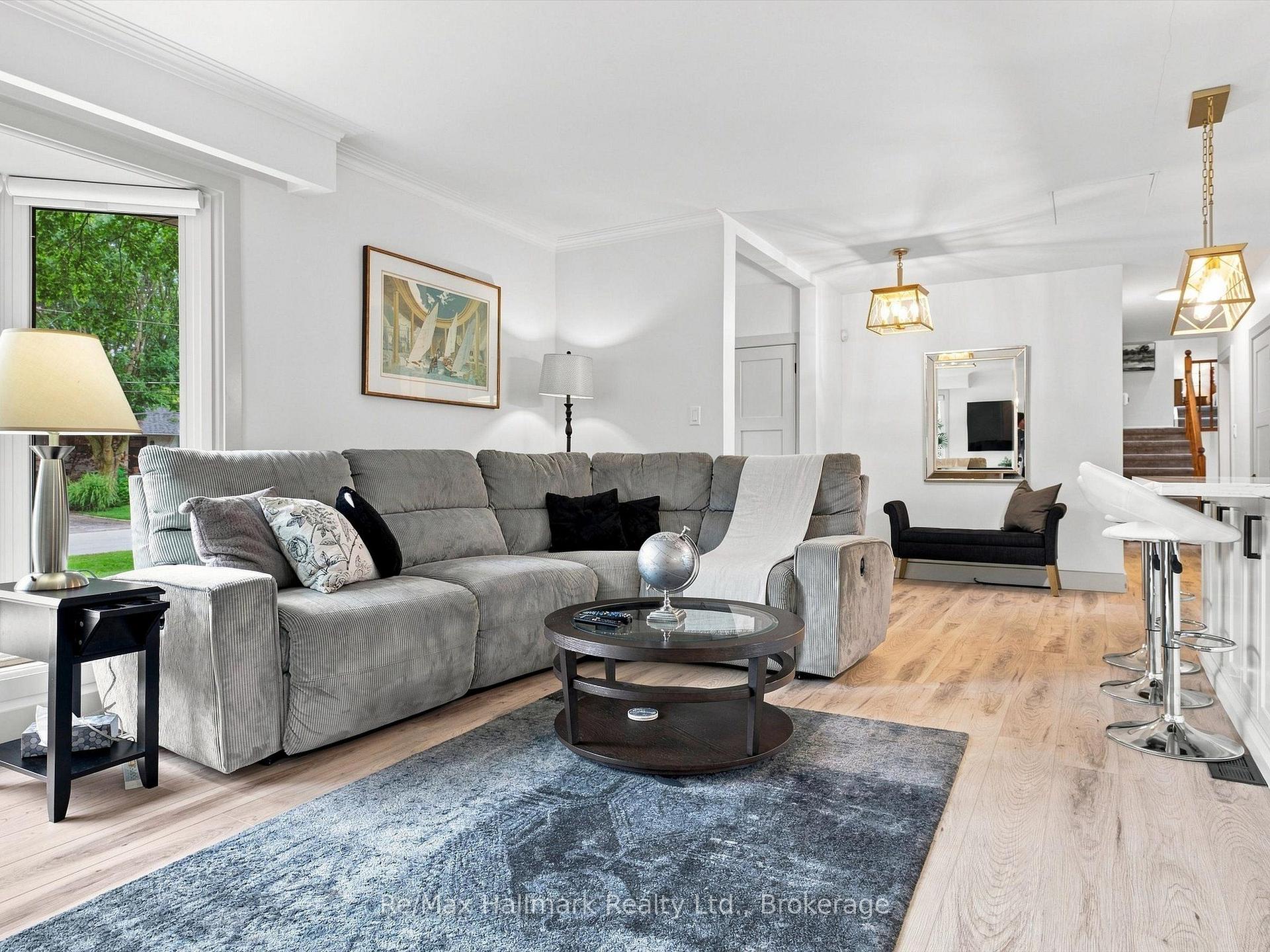 Living room with a gray sectional, round coffee table, and large window overlooking greenery.