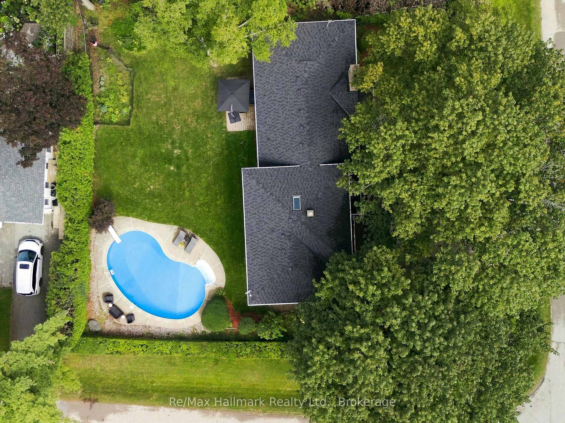 Aerial view of a tree-lined property with a kidney-shaped pool beside the home.