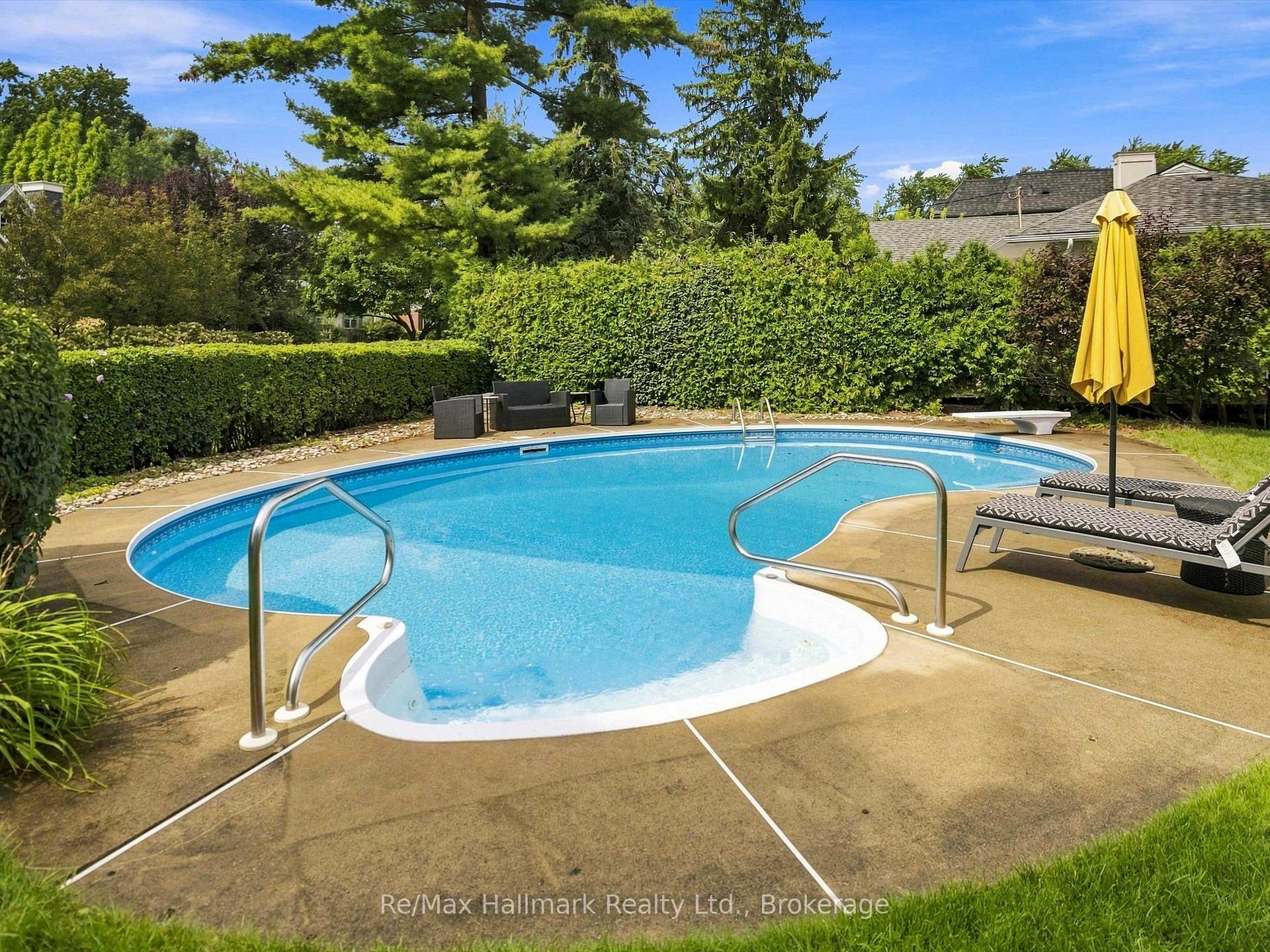 Backyard pool with curved entry steps, patio seating, and a yellow umbrella.
