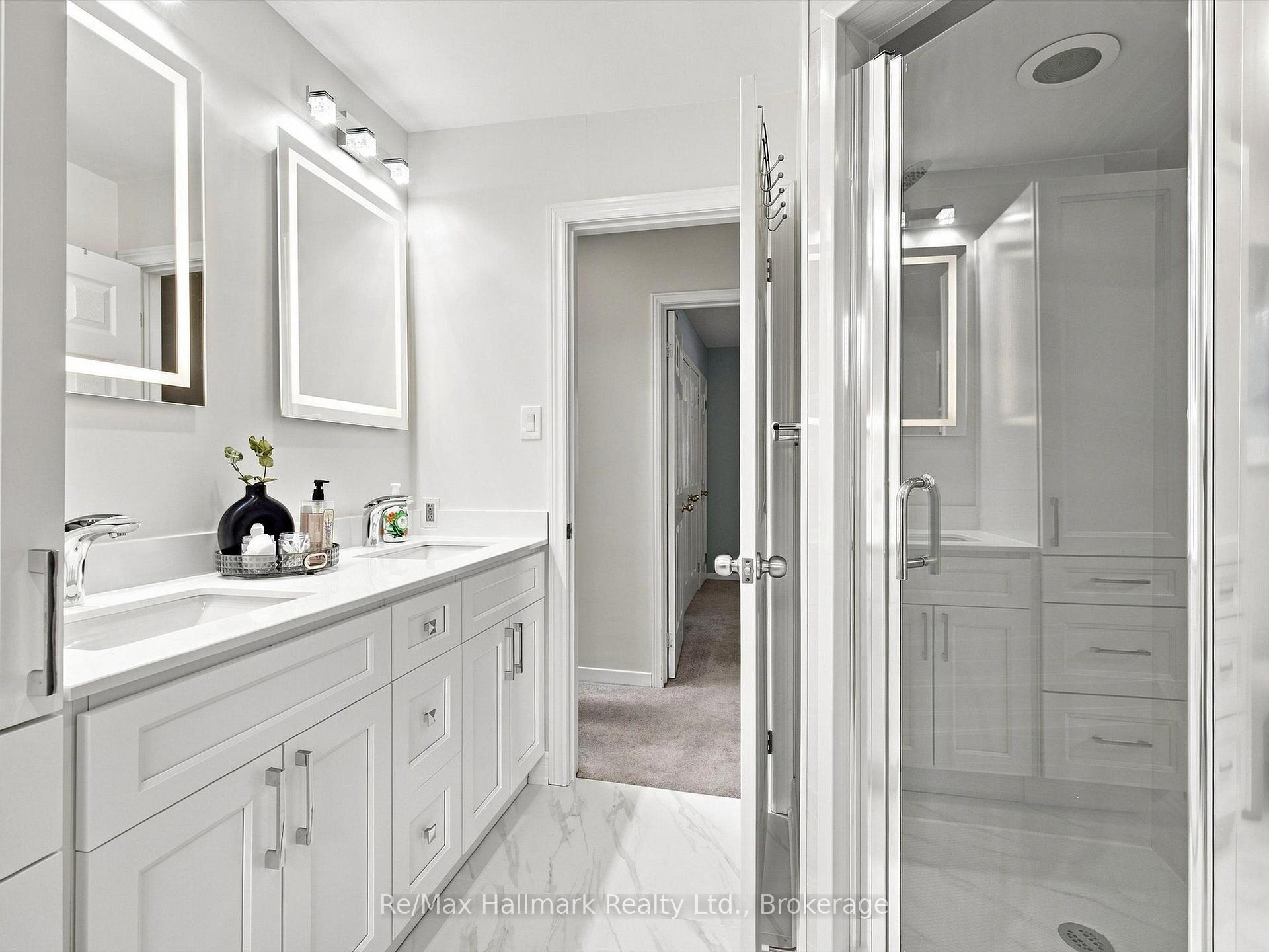 White bathroom with a long vanity and framed mirrors beside a glass-enclosed shower.