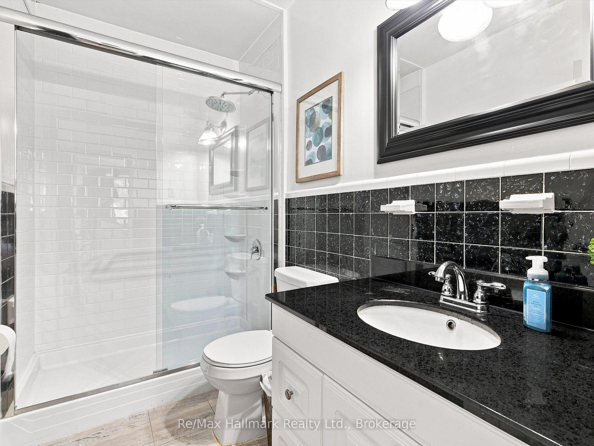Bathroom with glass shower, white subway tile, and a black granite vanity counter.