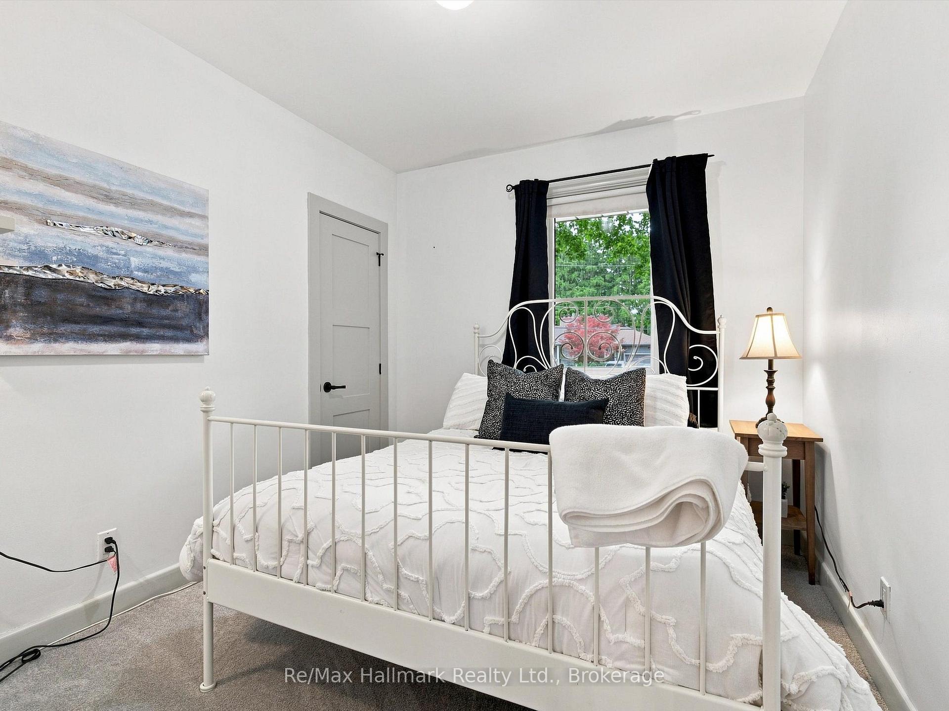 Bedroom with a white metal bed, textured bedding, dark curtains, and abstract wall art.
