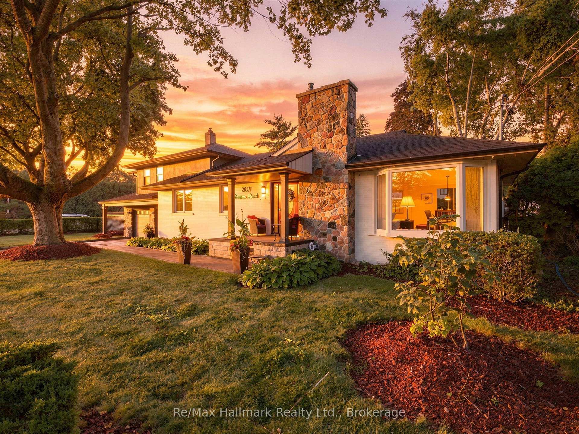 Oakville home with a prominent stone chimney and landscaped lawn at sunset.