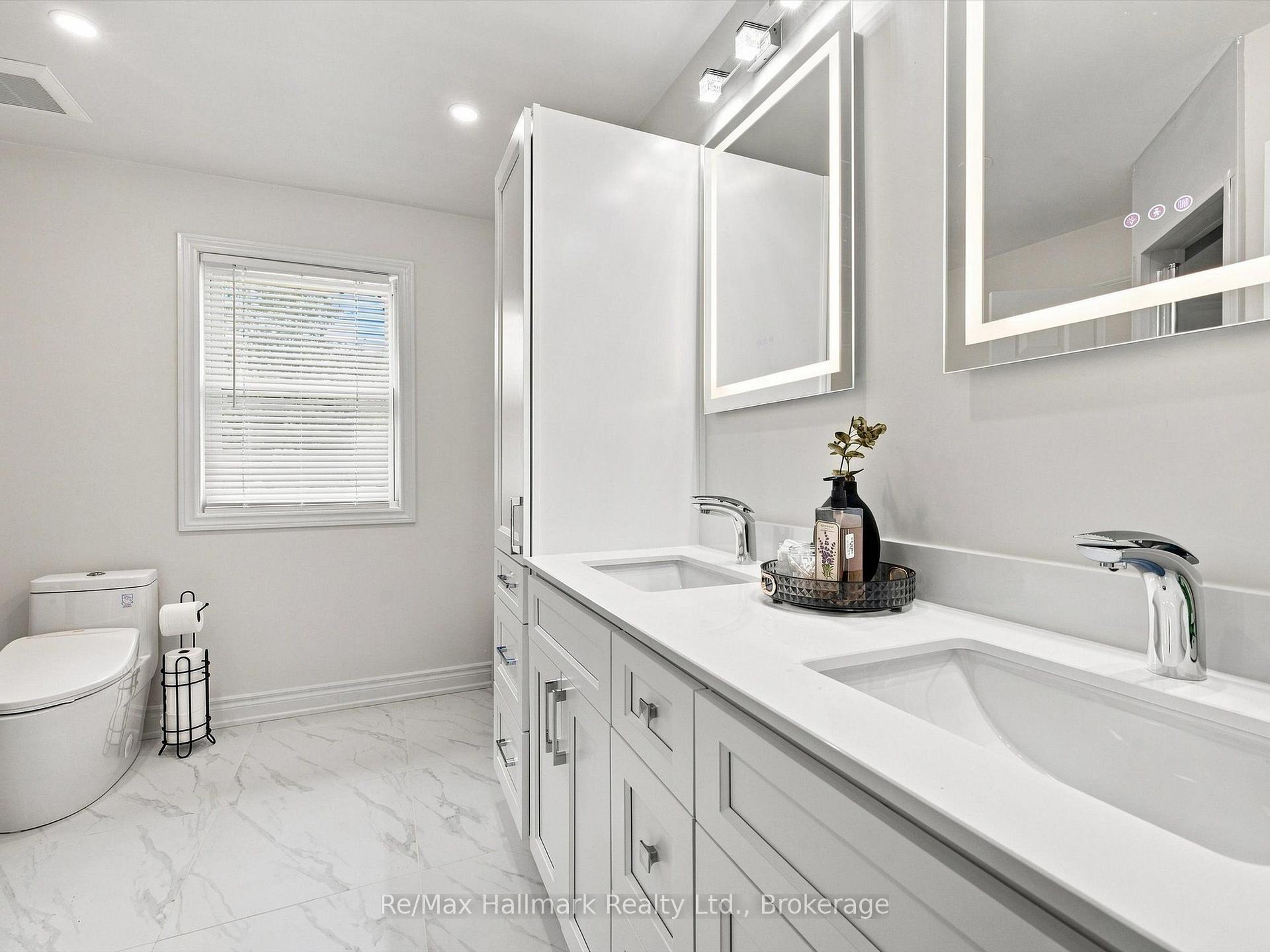Modern bathroom with a double-sink vanity, large mirrors, and marble-look tile flooring.