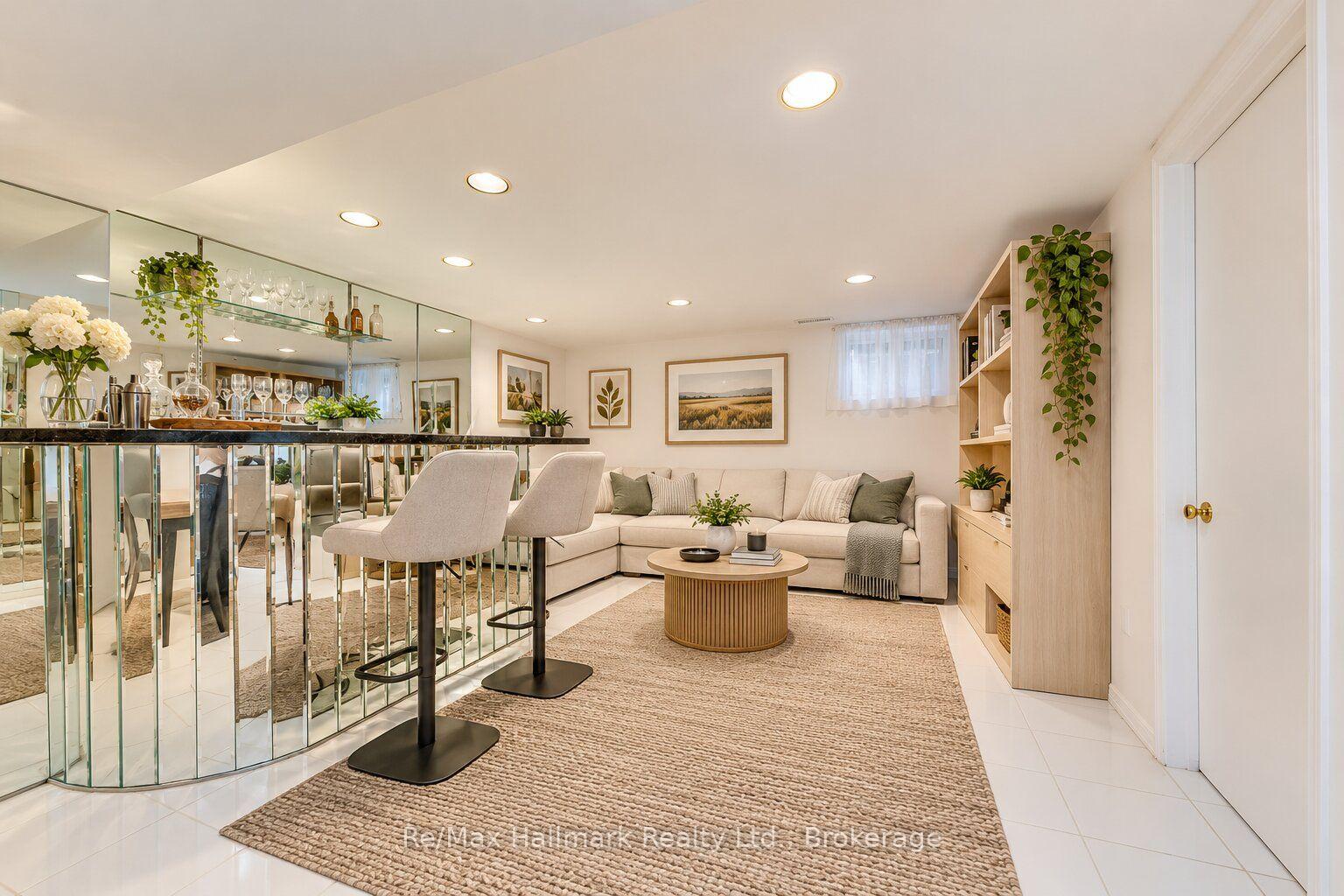 Furnished sitting area with a cream sectional, mirrored bar, and light wood shelving.