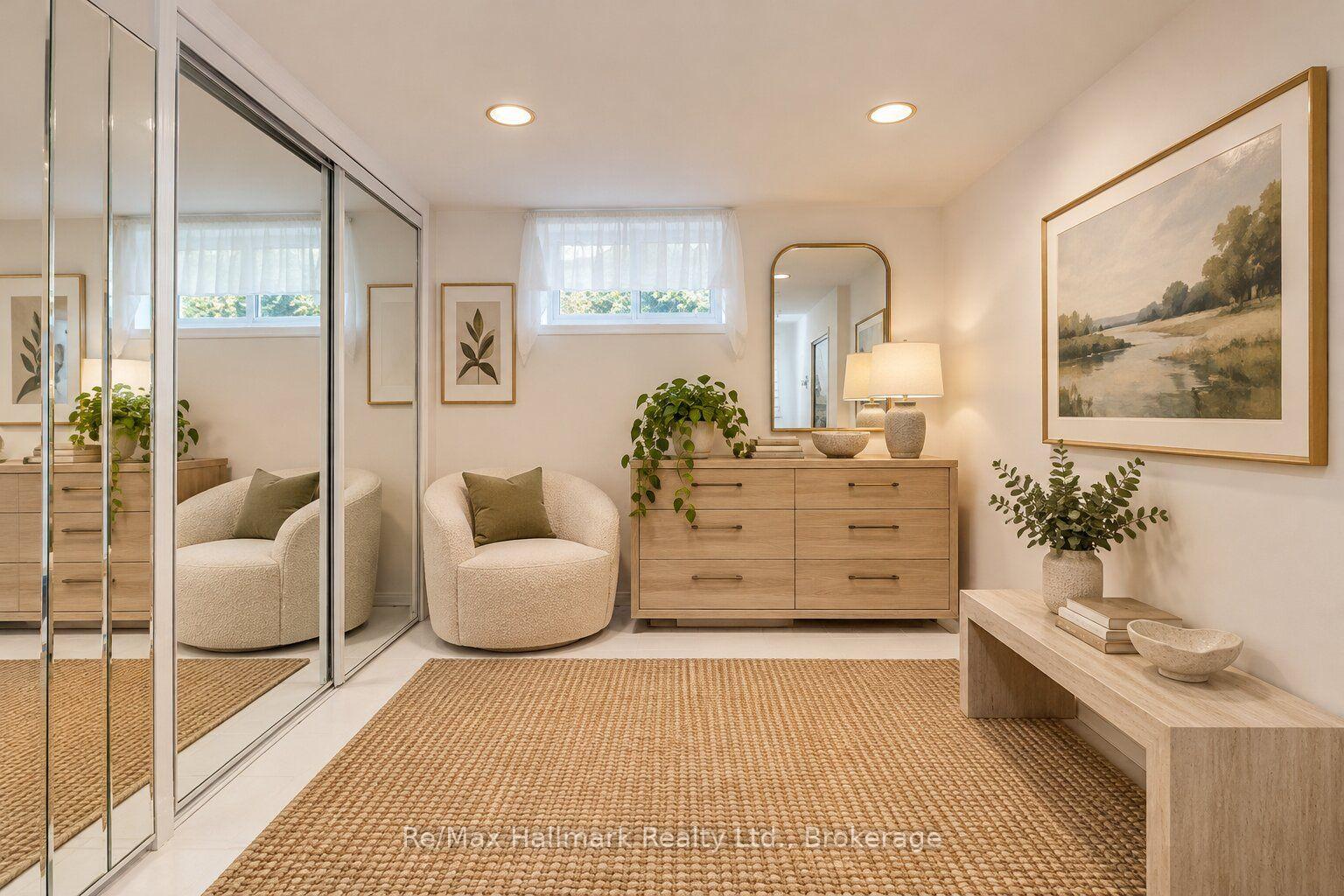 Staged dressing area with mirrored closet doors, a cream chair, and a wood dresser.
