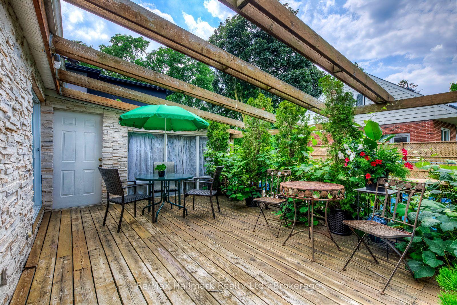 Wooden deck patio with a pergola, green umbrella, and outdoor dining furniture.