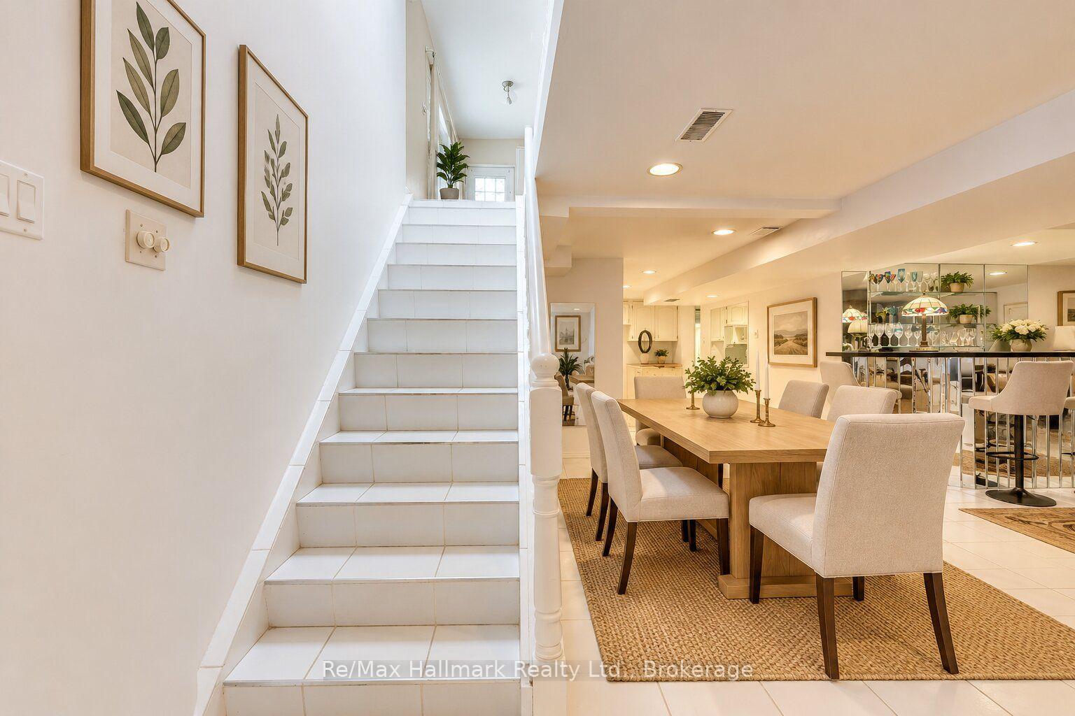 Dining room with a long wood table beside a white tiled staircase.