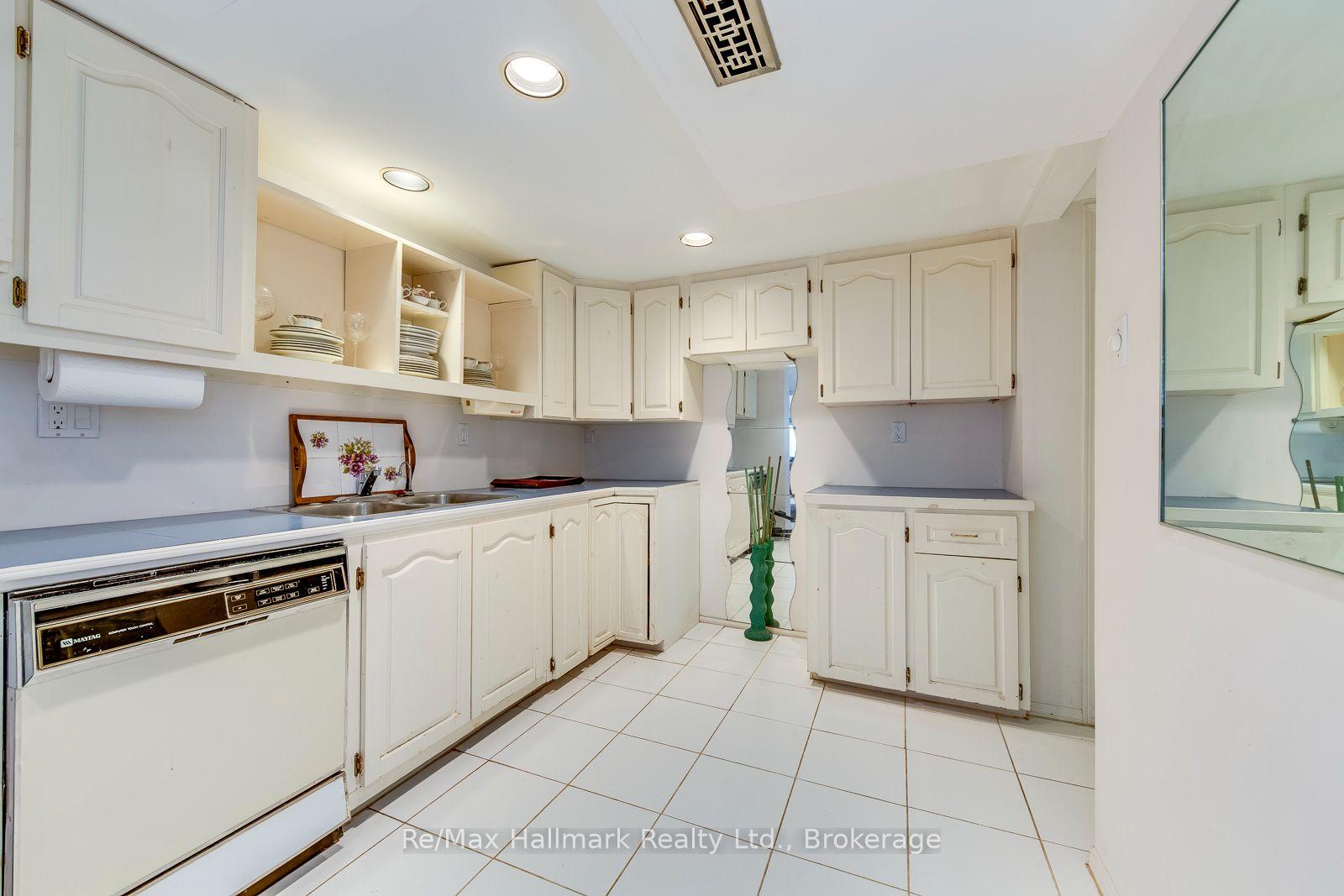 White kitchen with paneled cabinets, tiled floor, and a built-in dishwasher.
