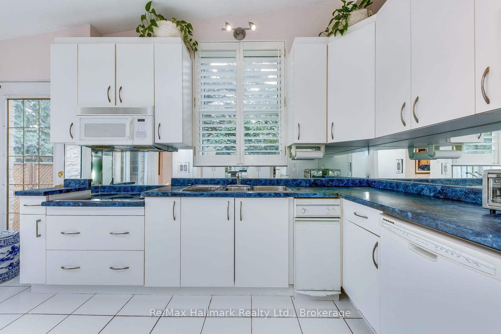 White kitchen with blue countertops, mirrored backsplash, and plantation shutters.