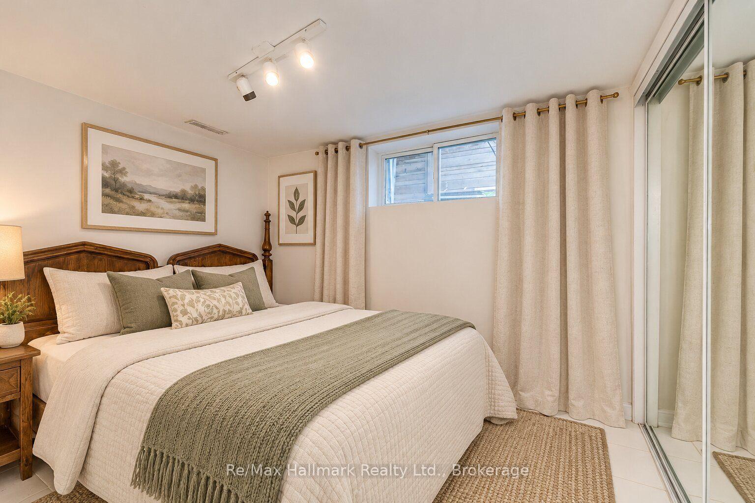 Bedroom with a dark wood bed, layered neutral bedding, and sliding glass doors.