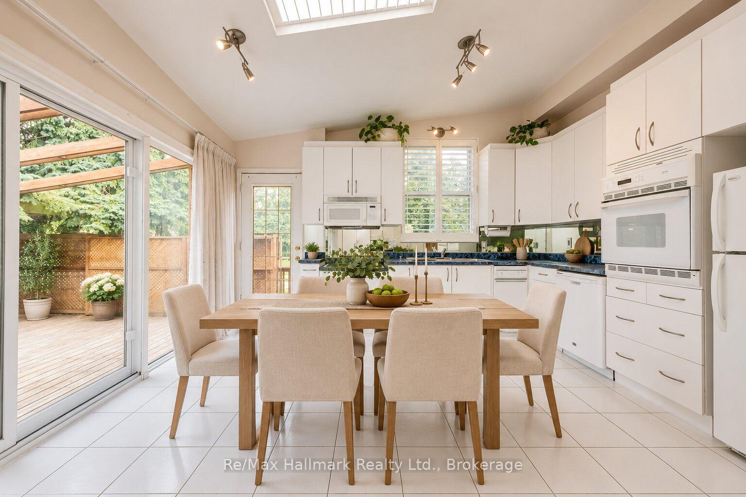 Bright white kitchen and dining area with a skylight and sliding doors opening to a deck.