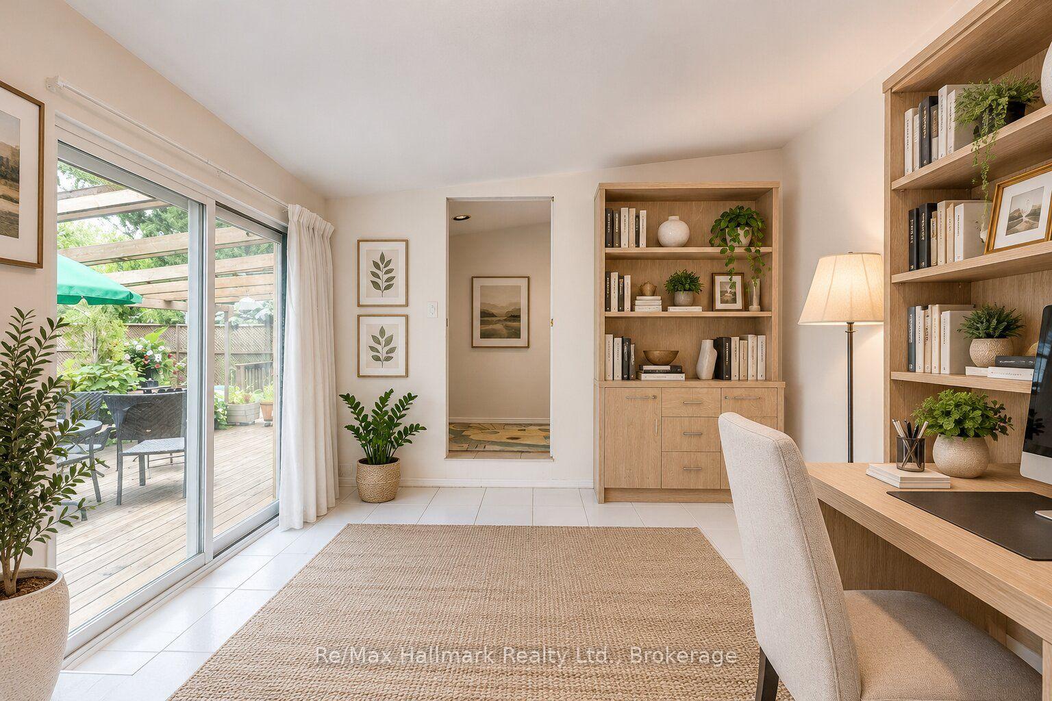 Home office with built-in wooden bookshelves and sliding doors opening to a garden patio.