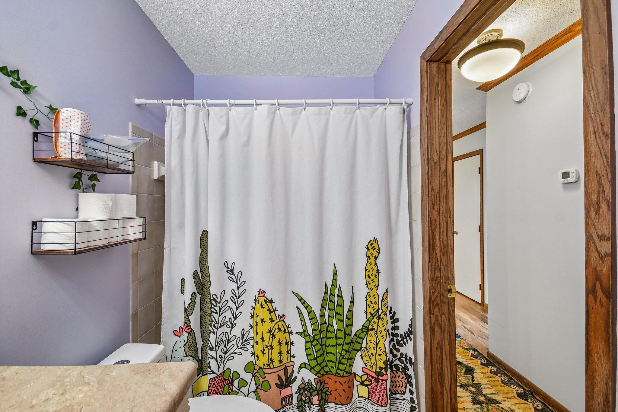 Bathroom with a colorful cactus-print shower curtain and lavender walls