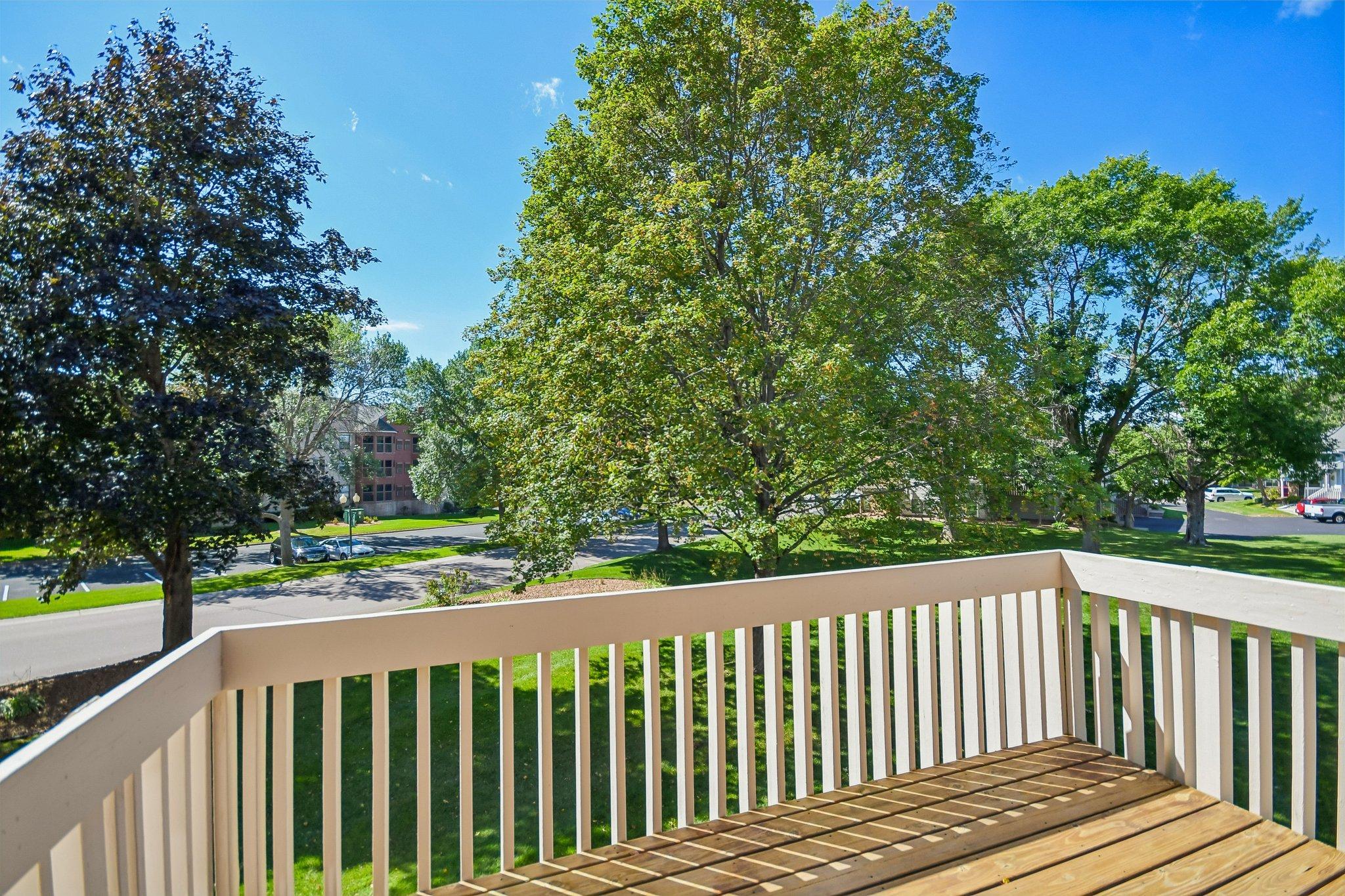 Deck overlooking a leafy lawn and tree-lined residential street.