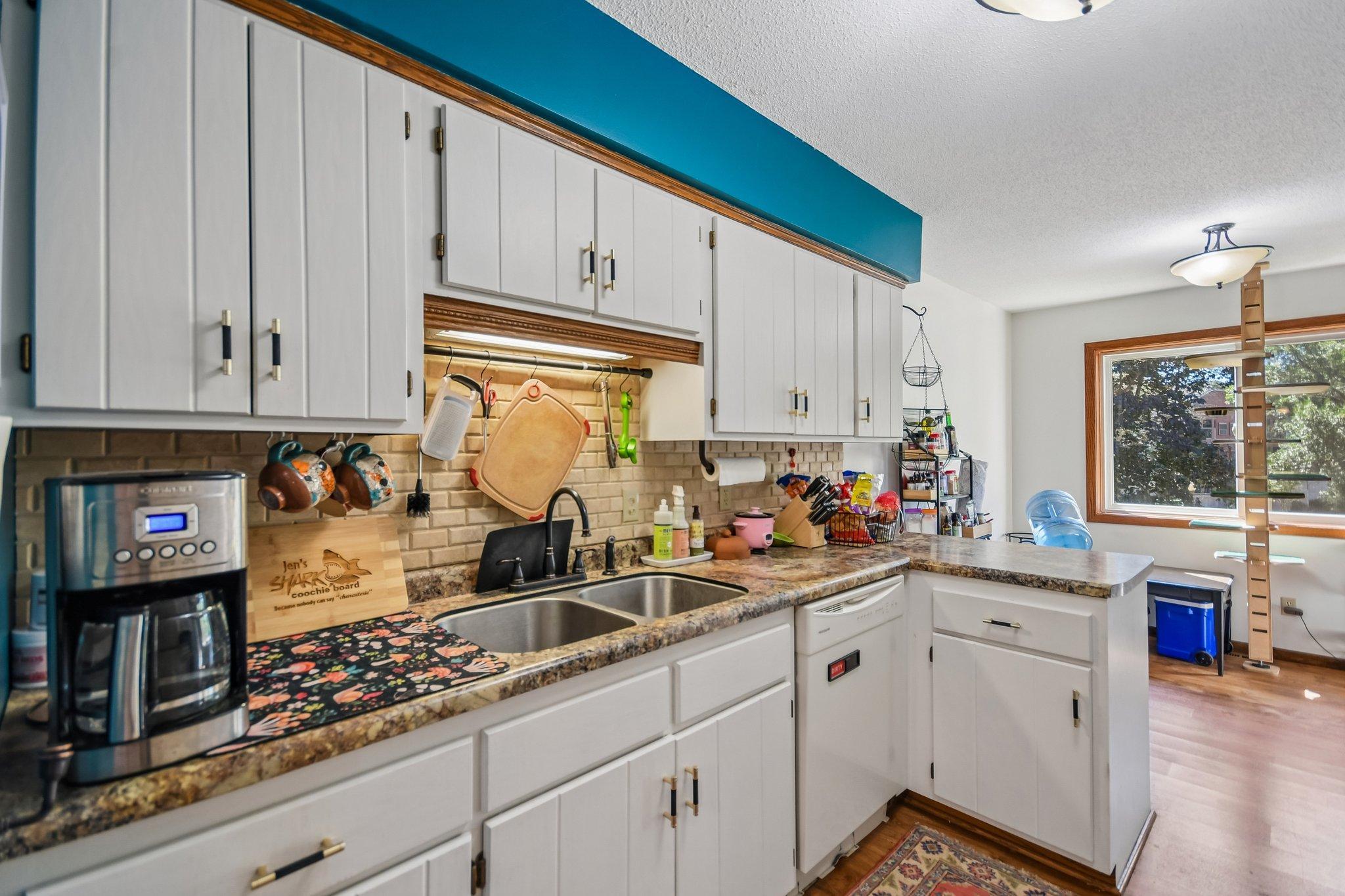 Kitchen with white cabinets, a double sink, granite-pattern counters, and a teal accent wall.
