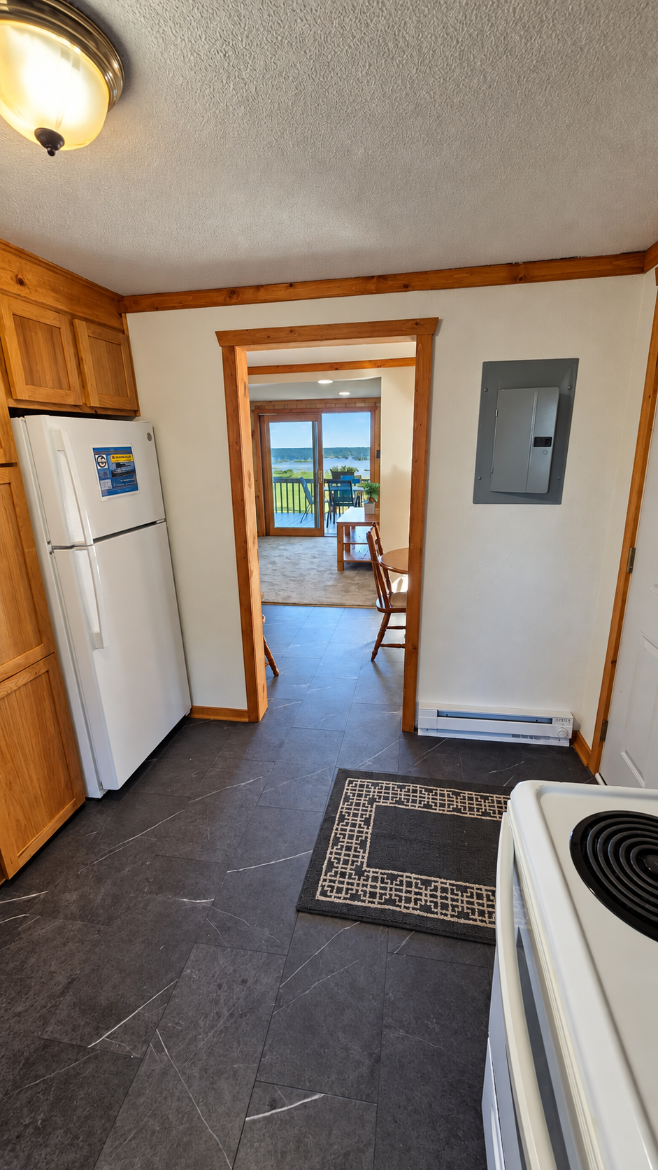 Kitchen with wood cabinets and dark tile floor, opening to a lake-view dining area and deck.