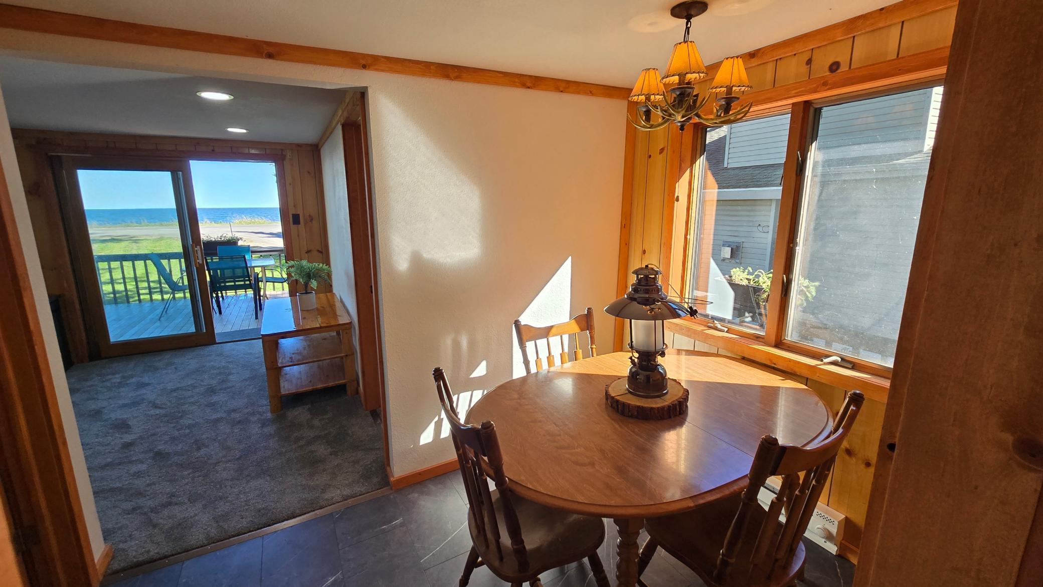 Dining room with a round wooden table, wood paneling, and lake views through the sliding glass door.