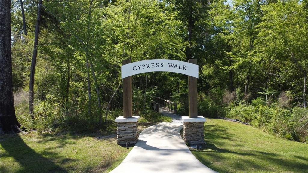 Cypress Walk entrance arch over a paved path into the woods.
