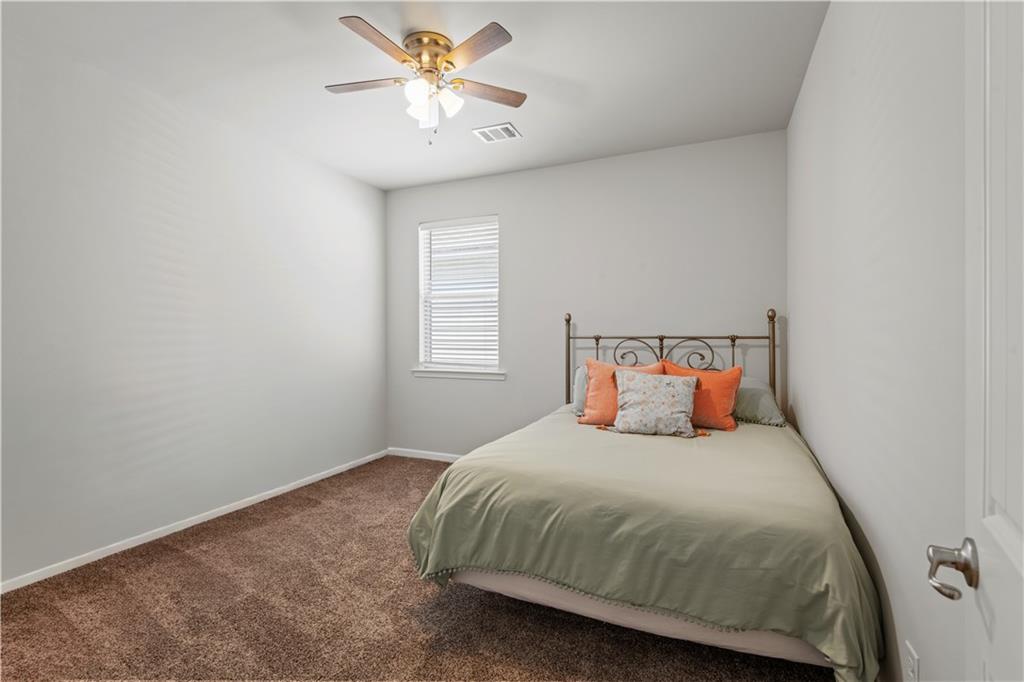 Furnished bedroom with sage-green bedding, orange pillows, and a metal scrollwork bed frame.