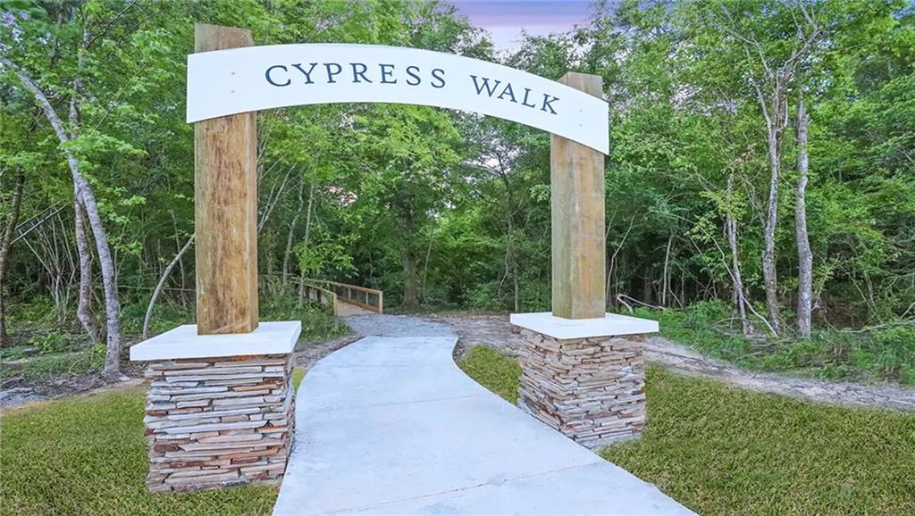 Cypress Walk entrance arch over a curved concrete path leading into the trees.