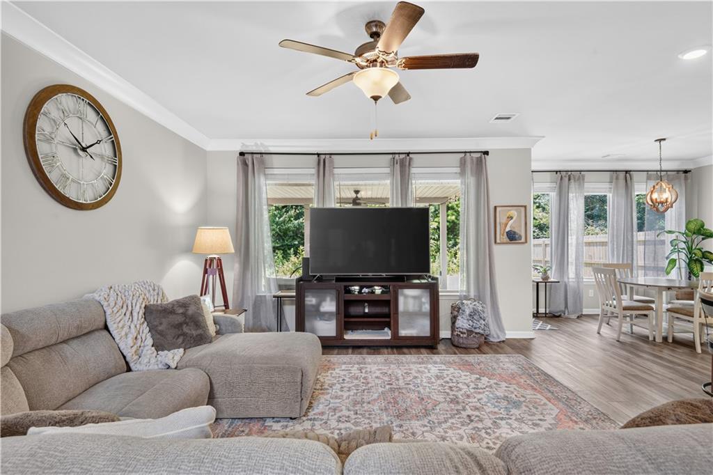 Living room with a large sectional, patterned rug, television, and windows overlooking greenery.