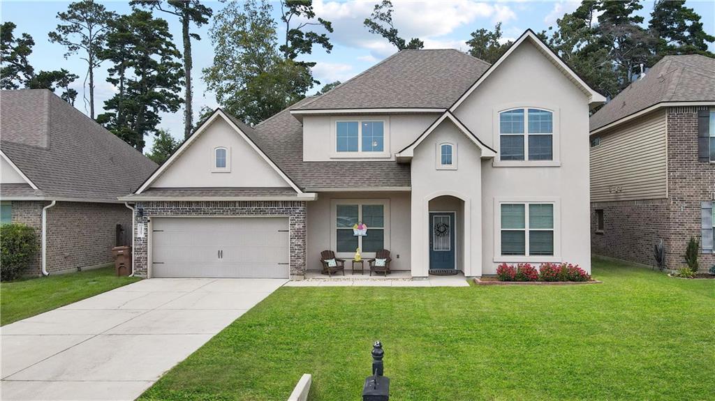 Two-story cream house with brick accents, double garage, covered entry, and wide driveway.