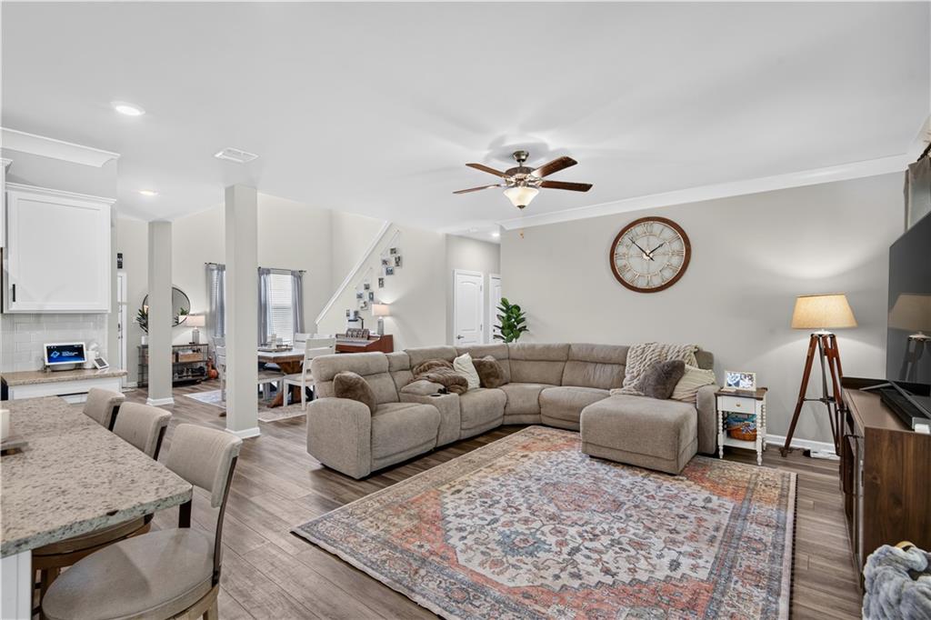 Open-plan living room with a large sectional sofa, patterned rug, and wall clock.