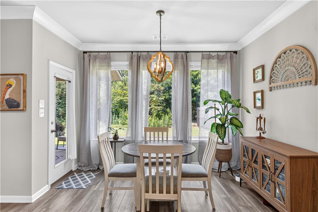 Dining room with a round table, sheer curtains, and garden views through large windows.