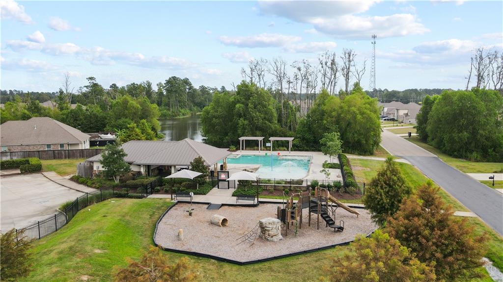 Aerial view of a neighborhood pool and playground beside a tree-lined waterway.