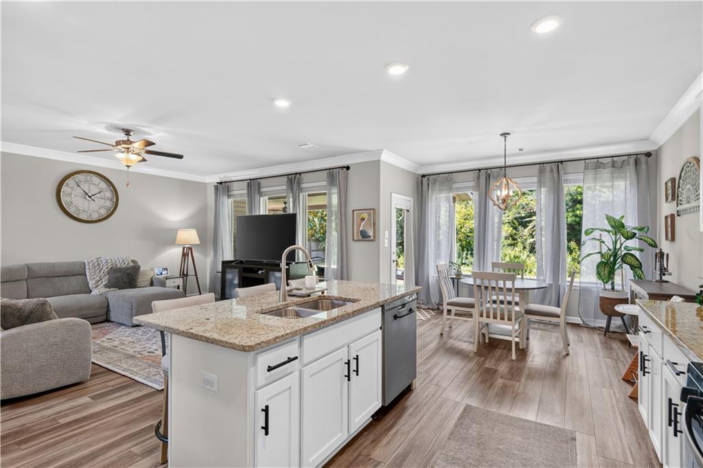 Open-plan kitchen and living area with a granite island, gray sofa, and tall windows.